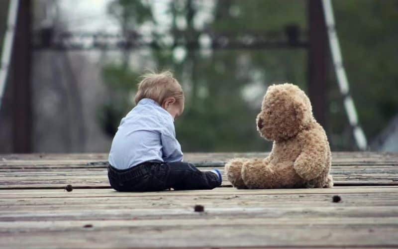 A baby sitting next to a teddy bear