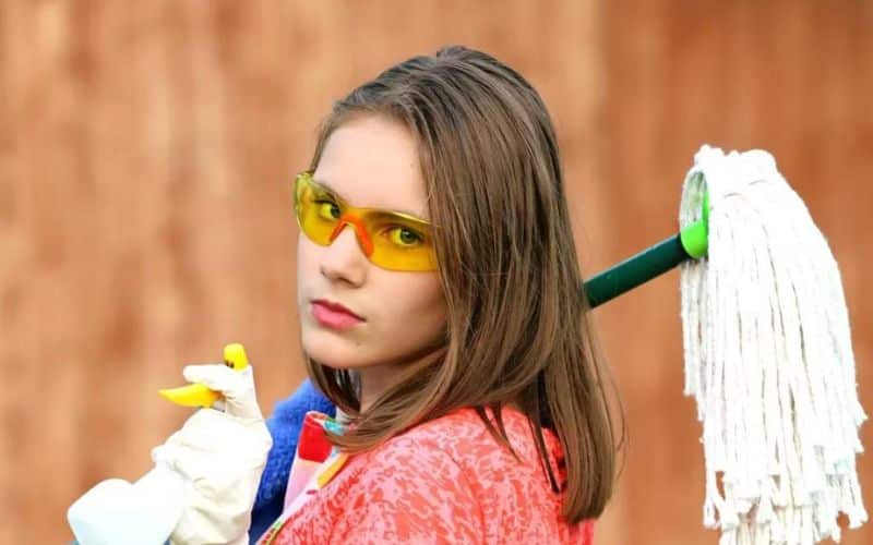 A lady holding a mop and tools for cleaning