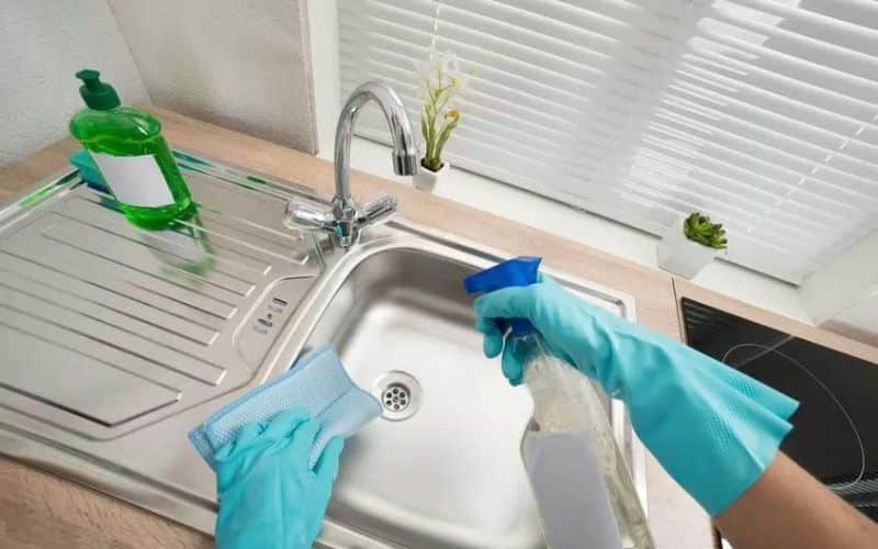 Cleaning the sink with a towel and a spray using own natural cleaner