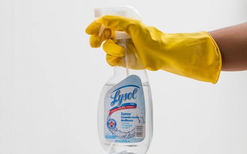 A man holding a bottle of lysol to kill mold