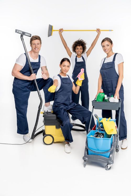 Four confident cleaning service professionals posing with cleaning equipment
