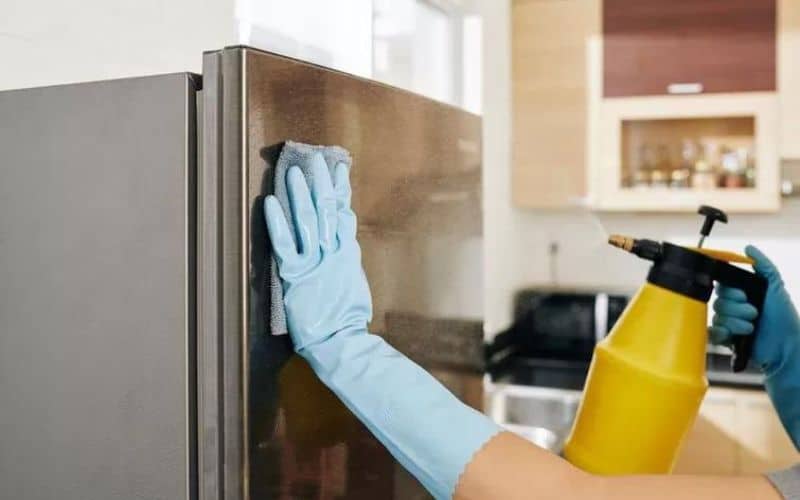 Spraying stainless steel refrigerator with DIY disinfectant spray