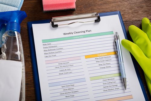 Weekly cleaning schedule clipped to blue clipboard