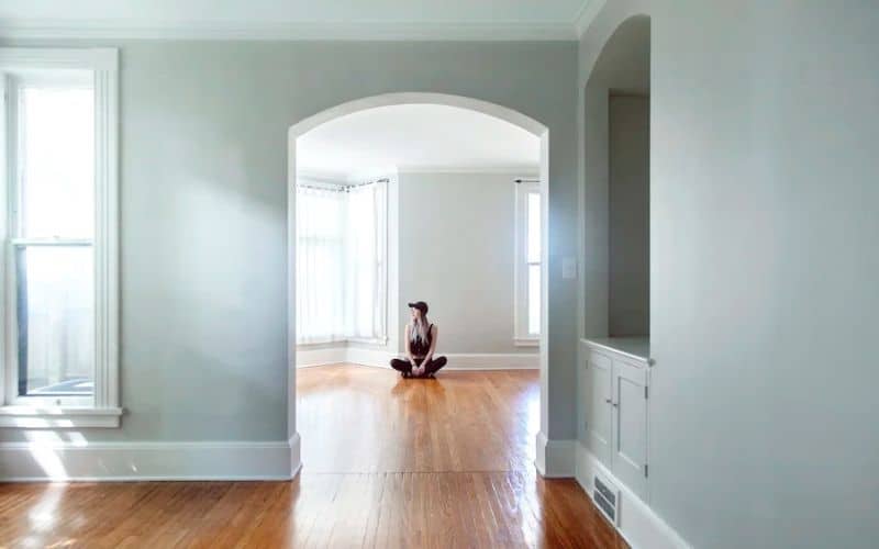 A woman sitting on the floor in an empty room