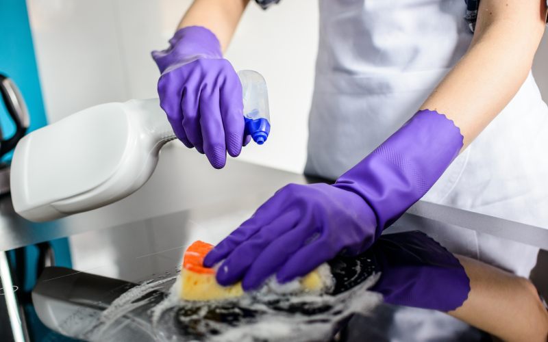 womans hands cleaning kitchen top rubber